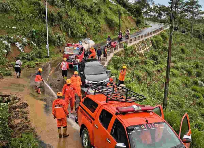 Petugas BPBD Wonosobo membersihkan material longsor yang menutup jalan di Kecamatan Watumalang.