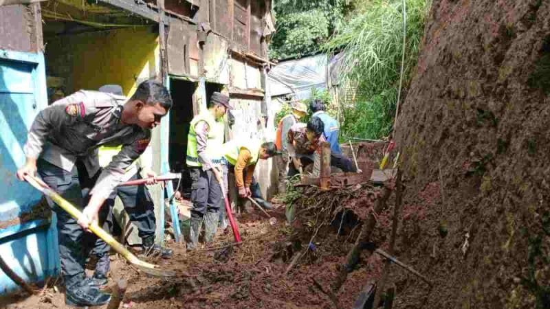 Petugas gabungan membersihkan material longsor yang merusak rumah warga Surengede, Kejajar, Wonosobo.