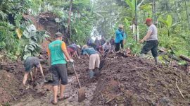 Warga bergotong royong membersihkan material tanah longsor.