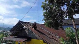 Warga melakukan perbaikan atap yang rusak terkena angin kencang.